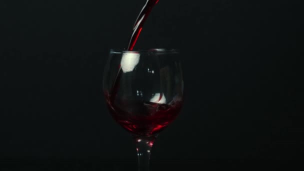 검은 배경의 술잔에 붉은 포도주를 뿌린다. 복사 공간으로 클로즈업 — 비디오