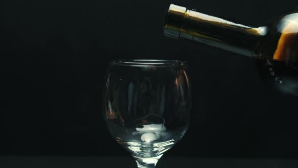 Anggur merah dituangkan dalam gelas piala, latar belakang hitam. — Stok Video