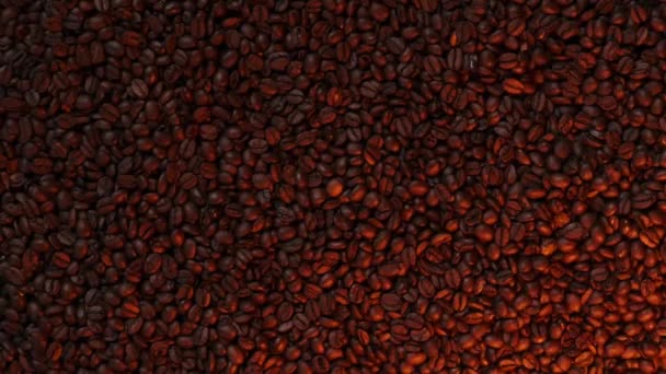 Grains de café dans un éclairage différent. Brun grains de café torréfié, quelqu'un à la main prend un grain. Fond brun. — Video
