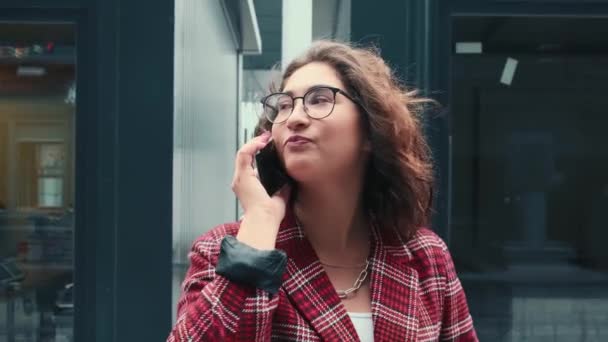 A young girl is talking on the phone. A girl communicates with colleagues in the open air with a cup of coffee in her hands. — Stock Video