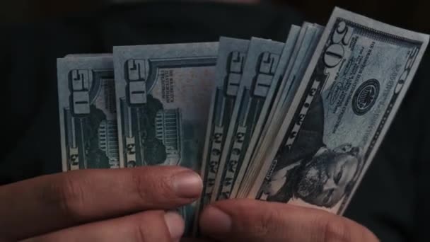 En person räknar dollar. Omräkning av pengar på svart bakgrund. Närbild av att räkna dollar. — Stockvideo