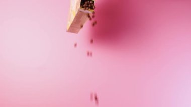 Mısır gevreğinden yapılmış çikolata topları pembe arka planda paketten düştü..