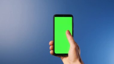 Elinde modern bir akıllı telefon olan genç bir adam üzerinde işaret işaretleri olan bir ekrana bakıyor. Yeşil ekran ve renk kavramı