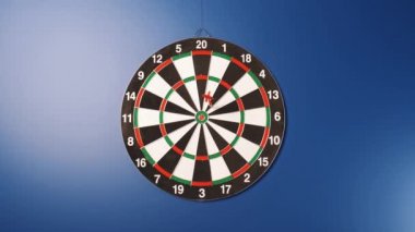 Dart oyunu. Hedefe dart atıyorlar. Ve birisi dart tahtasına dart atabilir. Mavi arka planda asılı bir dart tahtası.