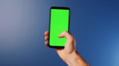 Elinde modern bir akıllı telefon olan genç bir adam üzerinde işaret işaretleri olan bir ekrana bakıyor. Yeşil ekran ve renk kavramı