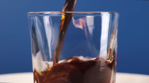 Pouring cola into a glass on a blue background. Static frame. 4k footage. — Stock Video