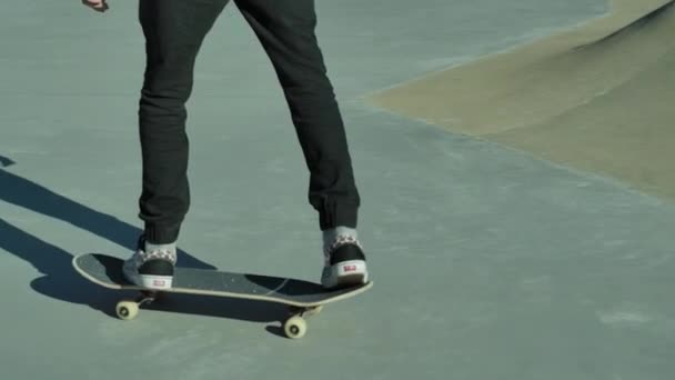 Slow motion video van een skateboarder die op een skateboard rijdt en trucs uithaalt met zijn skateboard buiten in een skatepark. — Stockvideo