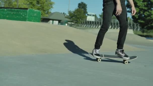 Video al rallentatore di uno skateboarder che cavalca uno skateboard e fa trucchi con il suo skateboard all'aperto in uno skate park. — Video Stock
