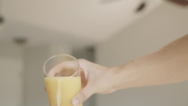 En närbild i slow motion av juice som hälls från ett genomskinligt glas. Nypressad juice. Juice till frukost. — Stockvideo