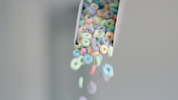 Cereais de pequeno-almoço na forma de anéis de milho coloridos são derramados fora do pacote. Fechamento de comida - para cima de flocos de milho coloridos e produtos lácteos. Movimento lento. — Vídeo de Stock