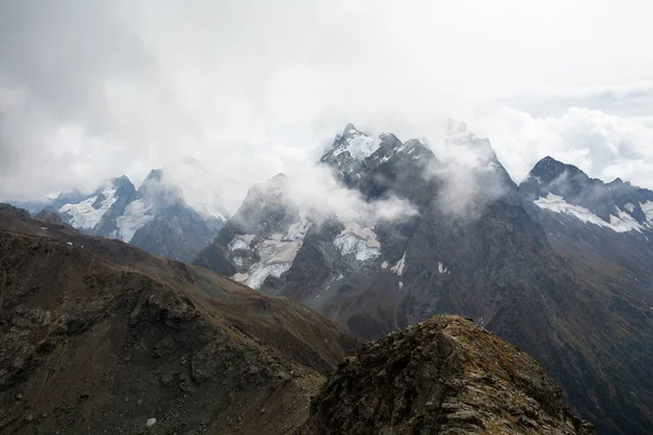 Snow capped mountain range in the clouds. Caucasus, Russia — Stock Photo, Image