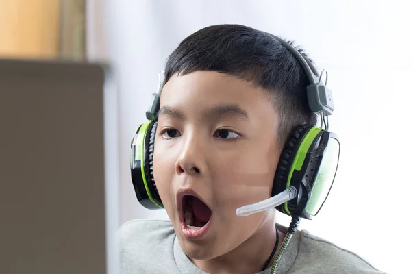 เด็กเอเชียเล่นเกมคอมพิวเตอร์ด้วยใบหน้าที่น่าประหลาดใจ — ภาพถ่ายสต็อก