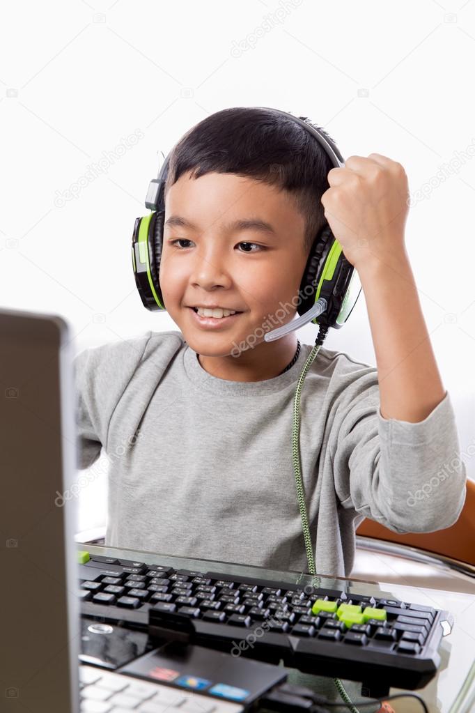 Asian kid play computer games with victory gesture