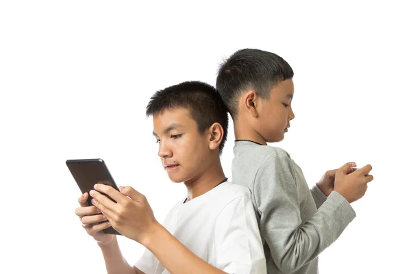 วัยรุ่นเอเชียและน้องชายของเขาบนแท็บเล็ตและสมาร์ทโฟน — ภาพถ่ายสต็อก
