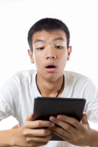 Asian teenager using his tablet or ipad with the surprise on his — Stock Photo, Image