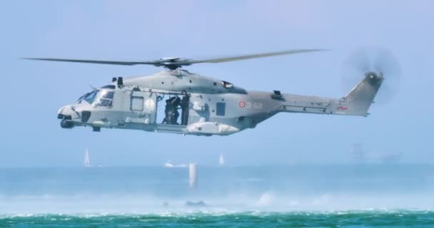 Śmigłowiec w unoszący się nad wodą zrzuca żołnierzy. Szary nowoczesny włoski Navy NHIndustries NH90 — Wideo stockowe