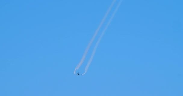 Militärflugzeug im Flug mit zwei weißen Rauchspuren am blauen Himmel — Stockvideo