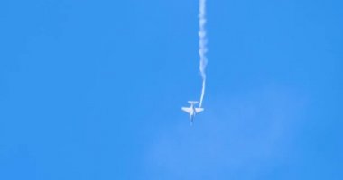 Beyaz izli mavi gökyüzünde uçan bir askeri jet.