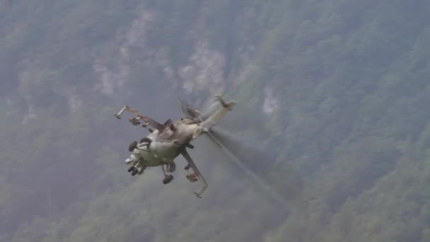 Крупный план ударного военного вертолета, выполняющего боевые манёвры вблизи гор — стоковое видео