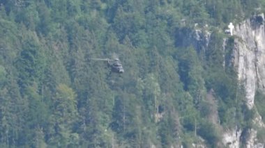 Askeri nakliye helikopteri bir dağın yakınında uçarak manevra yapıyor.