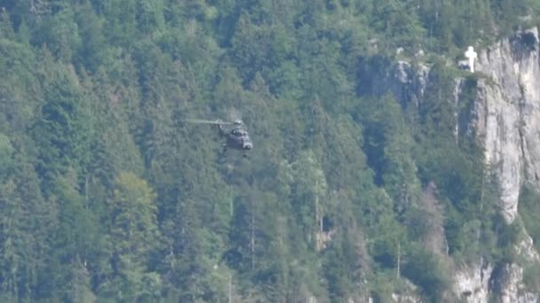 Helicóptero de transporte militar realiza maniobras volando cerca de una montaña — Vídeos de Stock