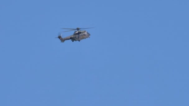 Helicóptero militar vuela en el cielo azul se eleva verticalmente girando sobre sí mismo — Vídeo de stock