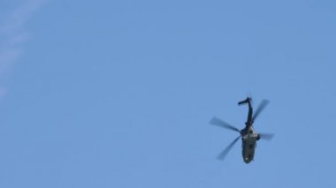 Askeri helikopter güneşli bir yaz gününde dağların arasında uçar.