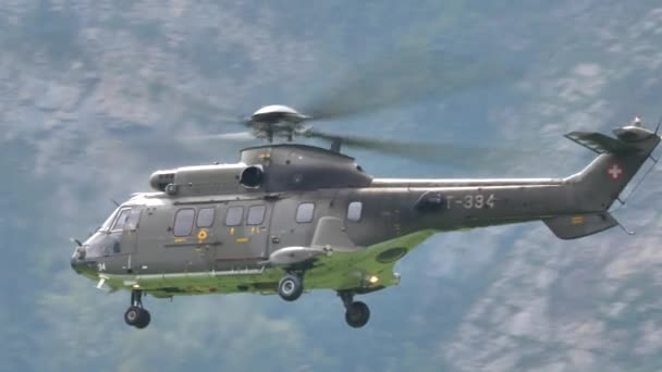 Close-up van militaire helikopter die achteruit vliegt en in een alpiene vallei draait — Stockvideo