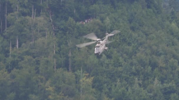Wojskowy śmigłowiec lecący z maksymalną prędkością zakamuflowany lasem w tle — Wideo stockowe