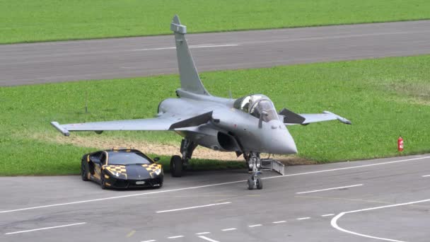 Avião de combate cinzento estacionado ao lado de um supercarro Lamborghini — Vídeo de Stock