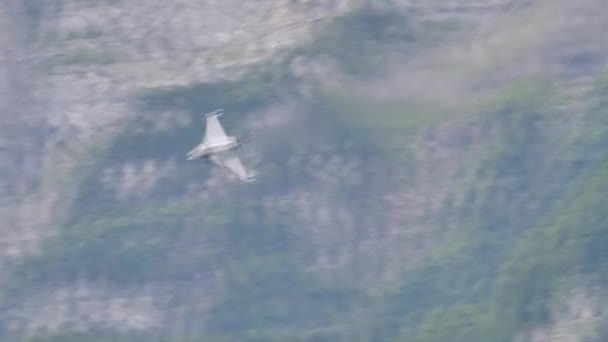 Военный истребитель выполняет ряд низкогорных валков в горной долине — стоковое видео