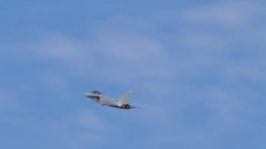 Güzel mavi gökyüzünde beyaz bulutlarla uçan savaş uçağı.