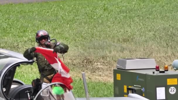 Pilot vojenského tryskáče stojící na katapultovacím sedadle rozevírá švýcarskou vlajku — Stock video