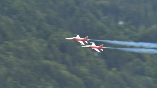 Zwei Militärflugzeuge fliegen dicht an dicht in einem engen Tal mit weißen Spuren — Stockvideo