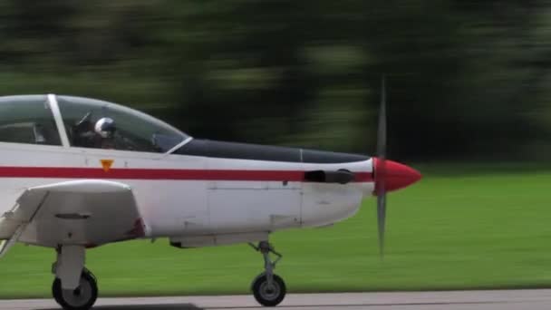 Close-up van rood-wit propellervliegtuig dat vertraagt op de baan na landing — Stockvideo