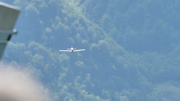 Frontal vy av och flygplan landning med grön skog som bakgrund — Stockvideo