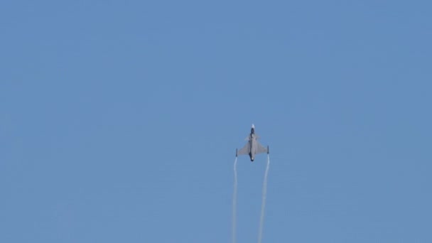 Kampfjet im Flug in blauem Himmel mit weißen Spuren — Stockvideo