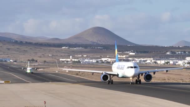 Avión taxiando en la pista de aterrizaje de cerca en un paisaje volcánico — Vídeos de Stock