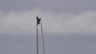 Modern bir askeri uçağın siyah silueti füzeleri yanıltmak için fişekler atıyor.