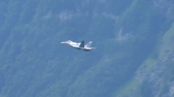 Langzame beweging van een straaljager trekken met groene bergen als achtergrond — Stockvideo