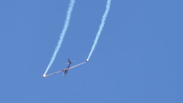 Аеробатичний планер виконує гармонійні трюки з димовими бомбами на синьому небі. — стокове відео