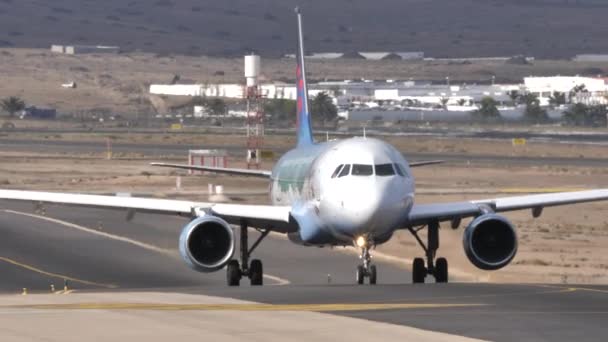 Vidsträckt utsikt över Lanzarotes flygplats och Airbus A320 som taxar på landningsbanan — Stockvideo