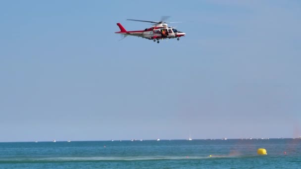 Helicóptero de bomberos Agusta A109 volando sobre el mar en una demostración de rescate — Vídeos de Stock