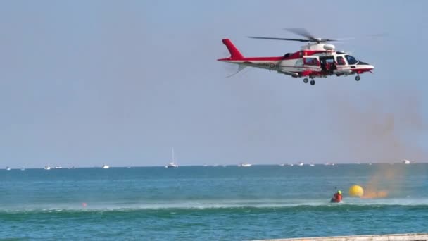 Team van brandweerlieden die oefening uitvoeren in het redden van de zee in helikopters die personen optillen — Stockvideo