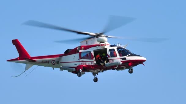 Equipe de bombeiros em um helicóptero vermelho e branco realizando broca de resgate marítimo — Vídeo de Stock