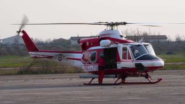 Brandweerman sluit de deur van de Agusta Bell AB-412 Grifone helikopter — Stockvideo