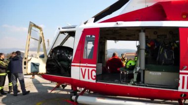 İnsanlar helikopterin etrafında toplanıp itfaiyecileri eğitiyorlar.