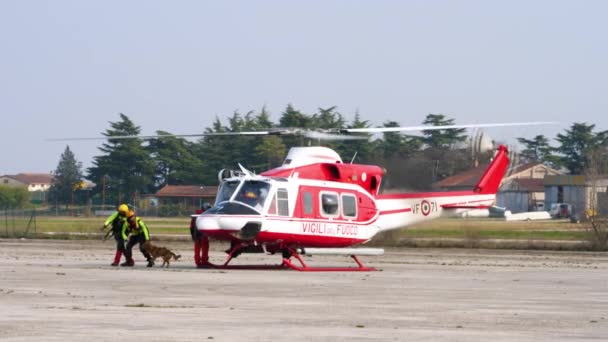 Brandweerlieden lopen uit helikopter Agusta Bell met getrainde reddingshond — Stockvideo