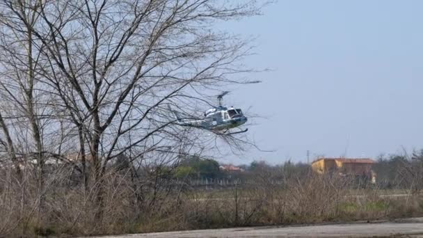 Helicóptero de policía Agusta Bell AB-212 volando detrás de los árboles y aterrizando — Vídeos de Stock