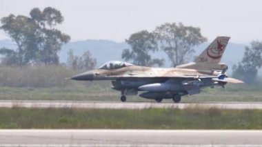 Kahverengi çöl kamuflajlı askeri bir uçağın yan görüntüsü piste vergi koyuyor.